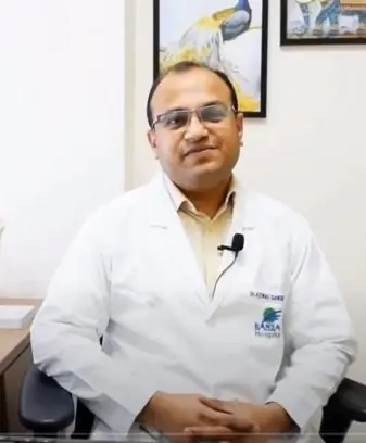 Dr. Kewal Gangrade in his medical office, wearing a white lab coat.