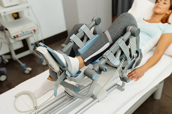 Patient undergoing physical therapy with a knee rehabilitation device.