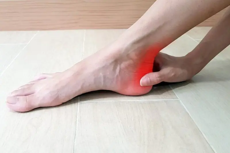 Close-up of a person holding their ankle, possibly due to pain or injury.